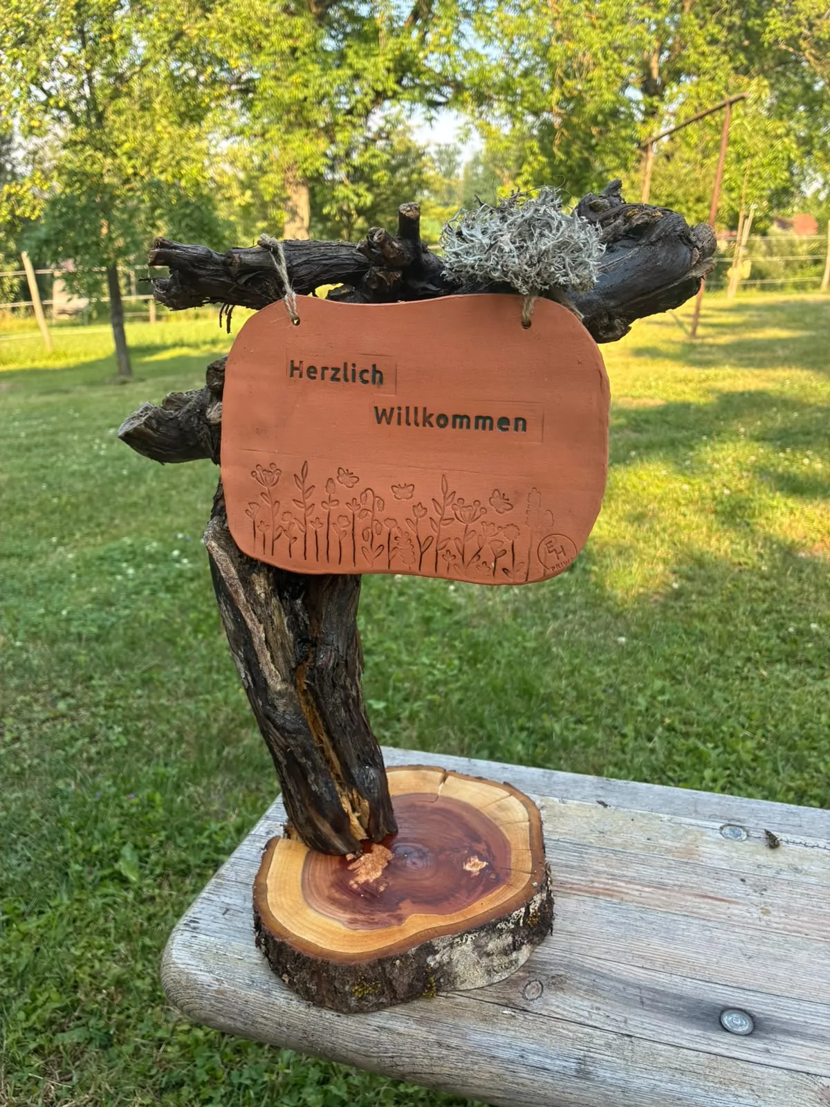 Baumscheiben-Aufsteller mit Tonschild „Herzlich Willkommen“ und eingravierter Blumenwiese
