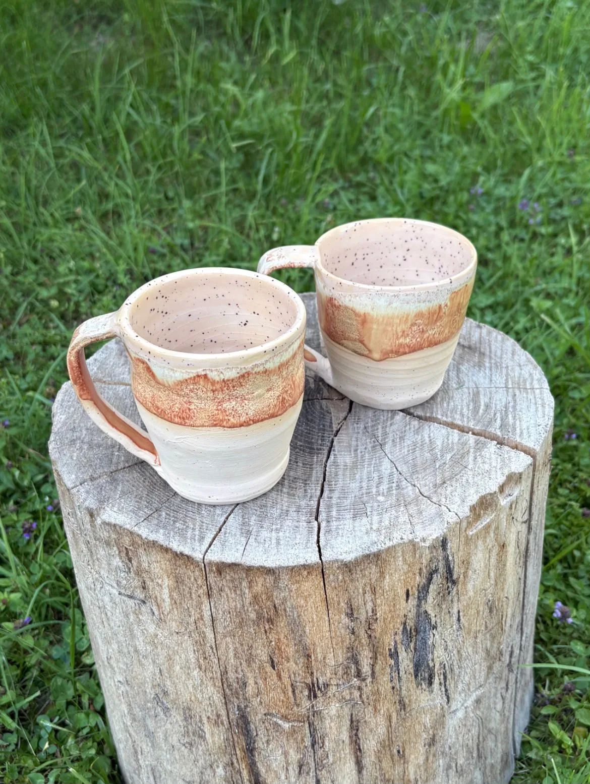 Zwei handgetöpferte Kaffeetassen mit erdigen Glasureffekten im Garten