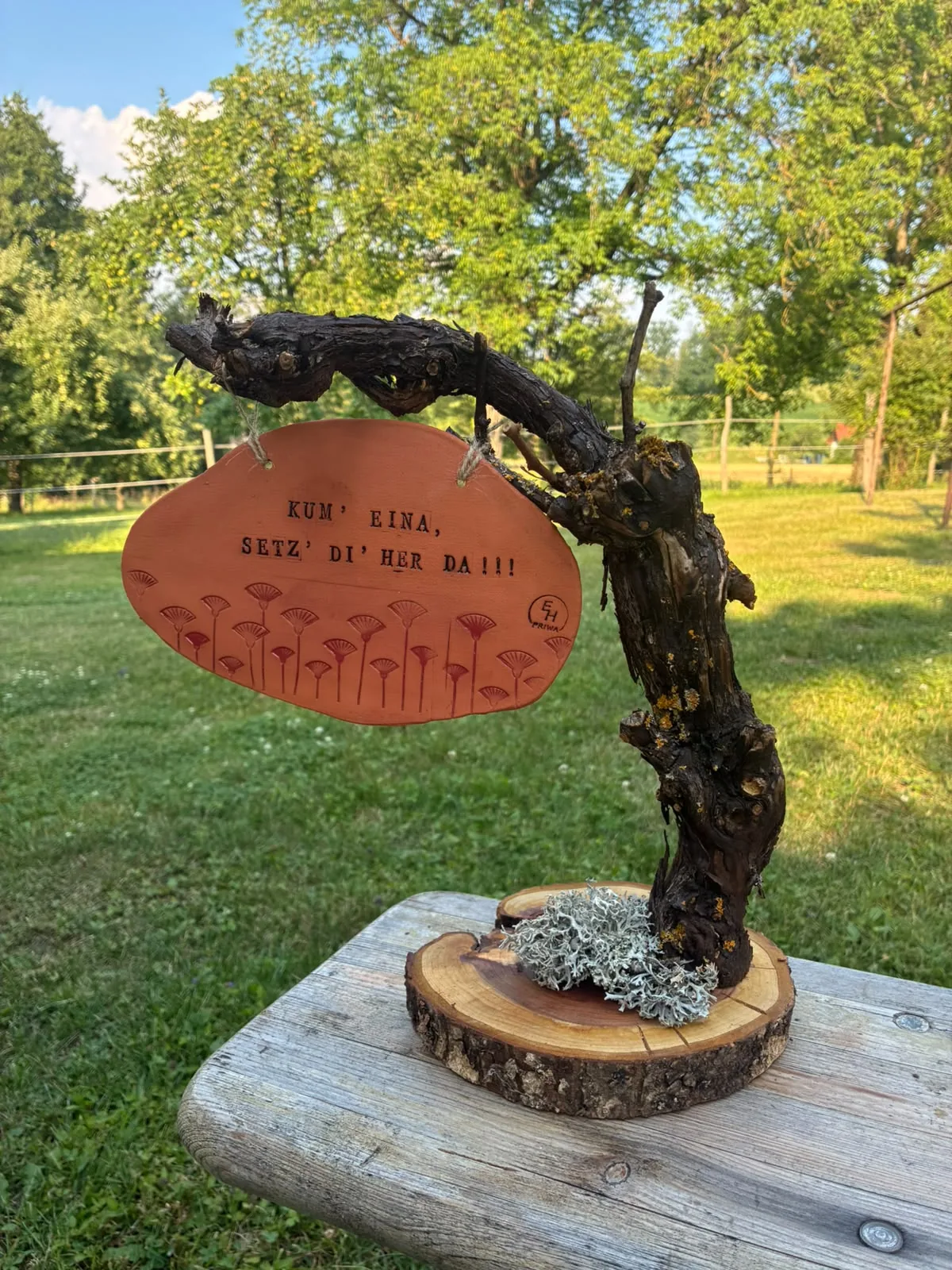 Kunstvolles Weinstock-Holz mit einem hängenden Tonschild auf einer Baumscheibe